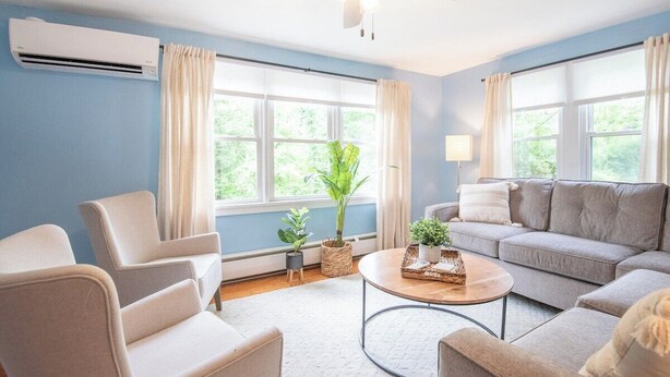 A living room with a ceiling fan, two sofas, a coffee table, and a window with curtains.