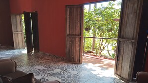 A room with patterned floor tiles, wooden doors, and brown upholstered chairs. - El Patio de Don Moncho - Shalpa (Jicalapa)