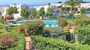 A residential area with a swimming pool surrounded by lush greenery and white buildings. - Apartamento Puerta del Sol (Conil de la Frontera)
