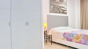 A hotel room with a bed, a nightstand, a lamp, a wardrobe, and a wall-mounted artwork. - Apartamento Puerta del Sol (Conil de la Frontera)