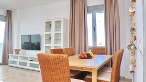 A dining area with a wooden table, wicker chairs, and a fruit bowl. - Apartamento Puerta del Sol (Conil de la Frontera)