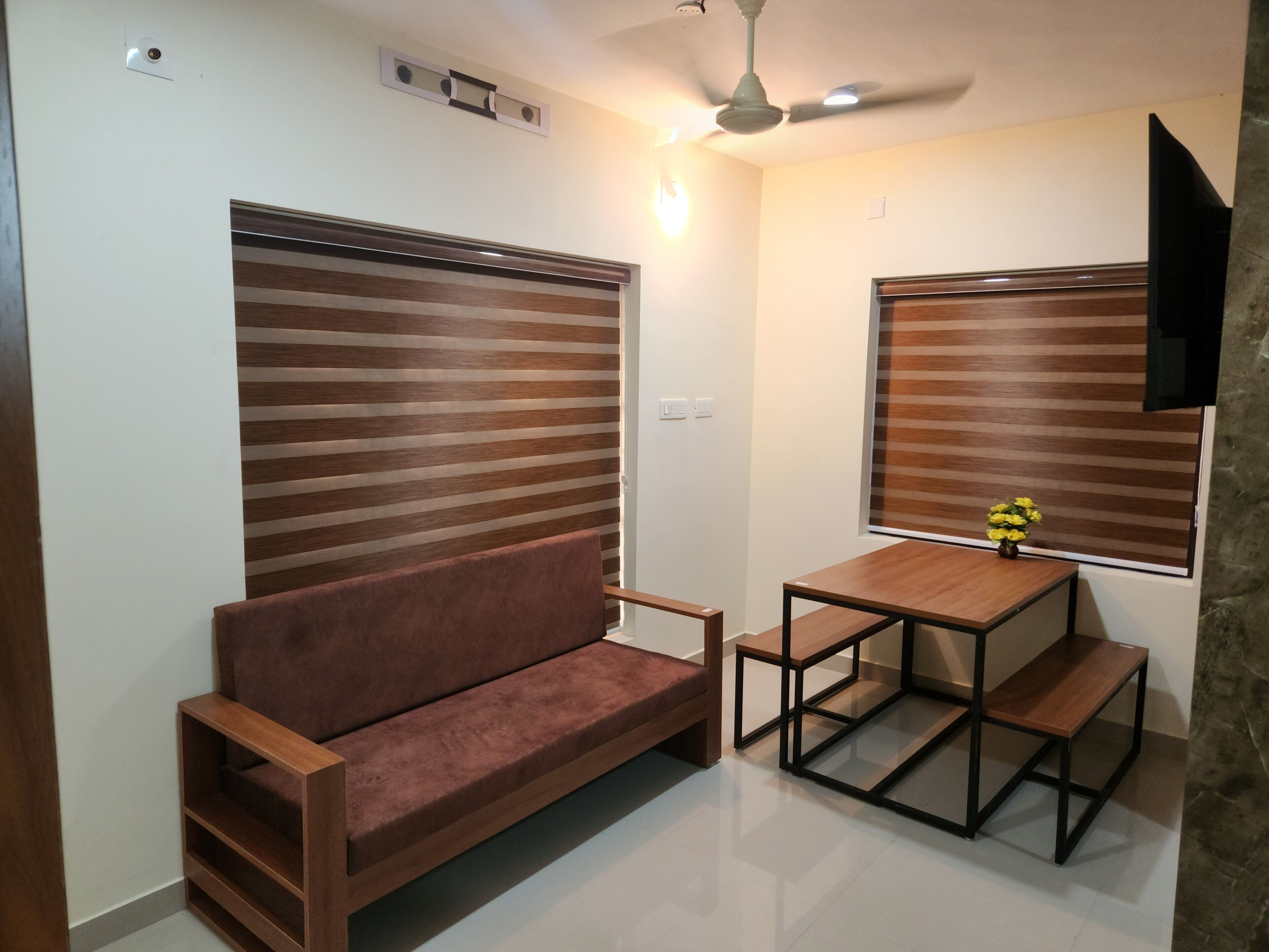 Un espace de vie compact comprenant un canapé, une petite table et un ventilateur de plafond.
