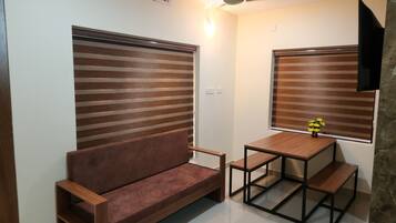 Un espace de vie compact comprenant un canapé, une petite table et un ventilateur de plafond.