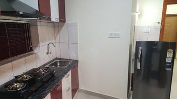 Eine Küche mit Gasherd, Spüle und einem schwarzen Kühlschrank.