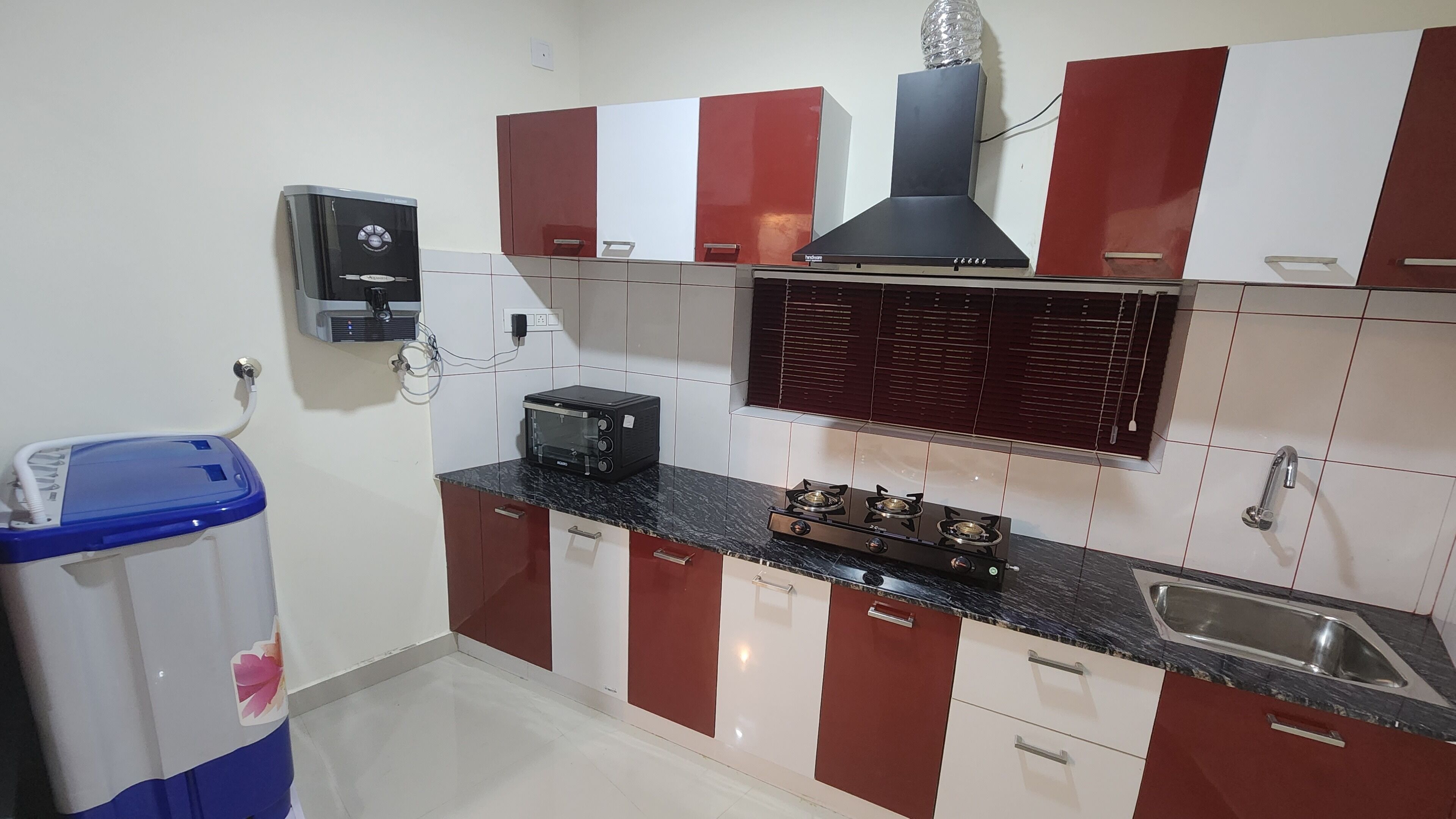 A compact kitchen with red and white cabinets, a built-in microwave, a gas stove, and a wall-mounted oven.