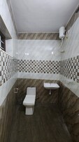 A bathroom with a marble floor, a toilet, a sink, and a shower.