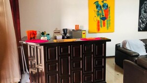 A living room with a dark wooden bar counter, a yellow painting, and a black sofa. - Serene one bedroom apartment in a quiet residential area, privacy assured  (Accra)