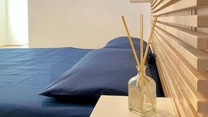Une chambre à coucher avec un lit, une table de chevet, une commode et une fenêtre avec des stores.