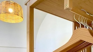 Une pièce en bois avec un portant suspendu et un luminaire en fibres tressées.