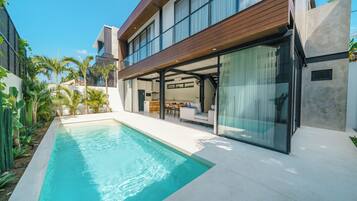 A modern house with a swimming pool, large windows, and a patio area.