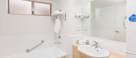 Un baño moderno con bañera, lavamanos y espejo.