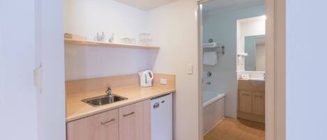 A compact kitchen with a sink, a coffee maker, and a dishwasher.