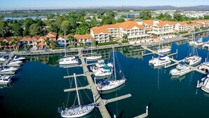 A marina with numerous boats docked, surrounded by residential buildings with red roofs. - Hope Harbour Hotel Apartments (Hope Island)