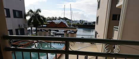 Ein Balkon mit zwei Stühlen, einem Pool und einem Yachthafen im Hintergrund.