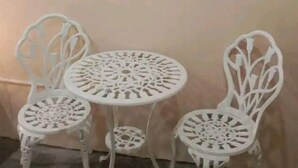 A room with a round table and two white chairs with intricate cut-out designs. There are two framed abstract paintings on the wall above the table. - TerisitaPlace Otél (Taytay)