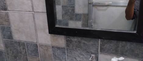 Un baño con un lavabo blanco, un espejo y un dispensador de jabón.