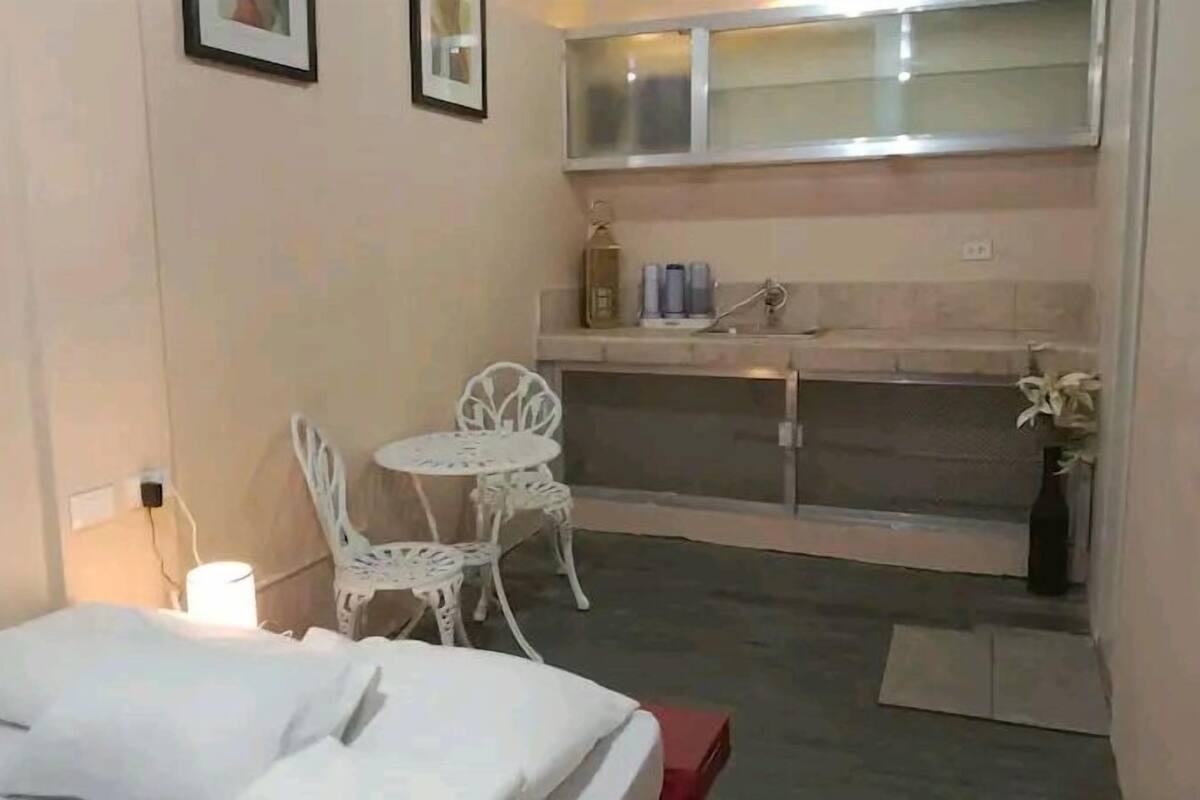 A compact room with a bed, a small table with chairs, a kitchenette, and a window.