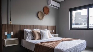 Una camera da letto moderna con un letto grande, una testiera in legno, un comodino e una finestra con vista sulla città.
