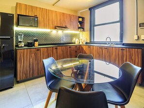 Enjoy meals at the central dining table surrounded by comfortable chairs, with a microwave and refrigerator nearby.