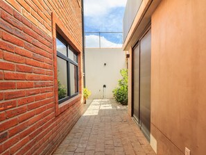 Stroll through this serene courtyard, surrounded by a brick wall and a light-colored wall, with a metal gate offering access to a building or another area.
