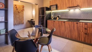 A modern kitchen with wooden cabinets, a black refrigerator, and a glass dining table with chairs. - Stylish, Private Flat with 1 BD by Tribu San Martin (Guadalajara)