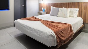 A modern hotel room with a large bed, a wooden headboard, a bedside table with a lamp, and a window with blinds. - Stylish, Private Flat with 1 BD by Tribu San Martin (Guadalajara)