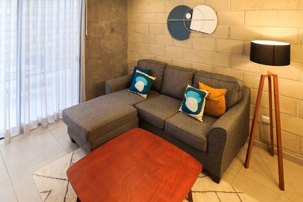 Sala de estar com sofá, apoio para os pés e luminária.