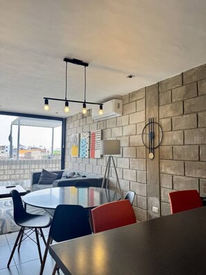 A modern dining area with a round table, chairs, and a brick wall. - Double Deluxe Apartment with Terrace - 406 (Guadalajara)