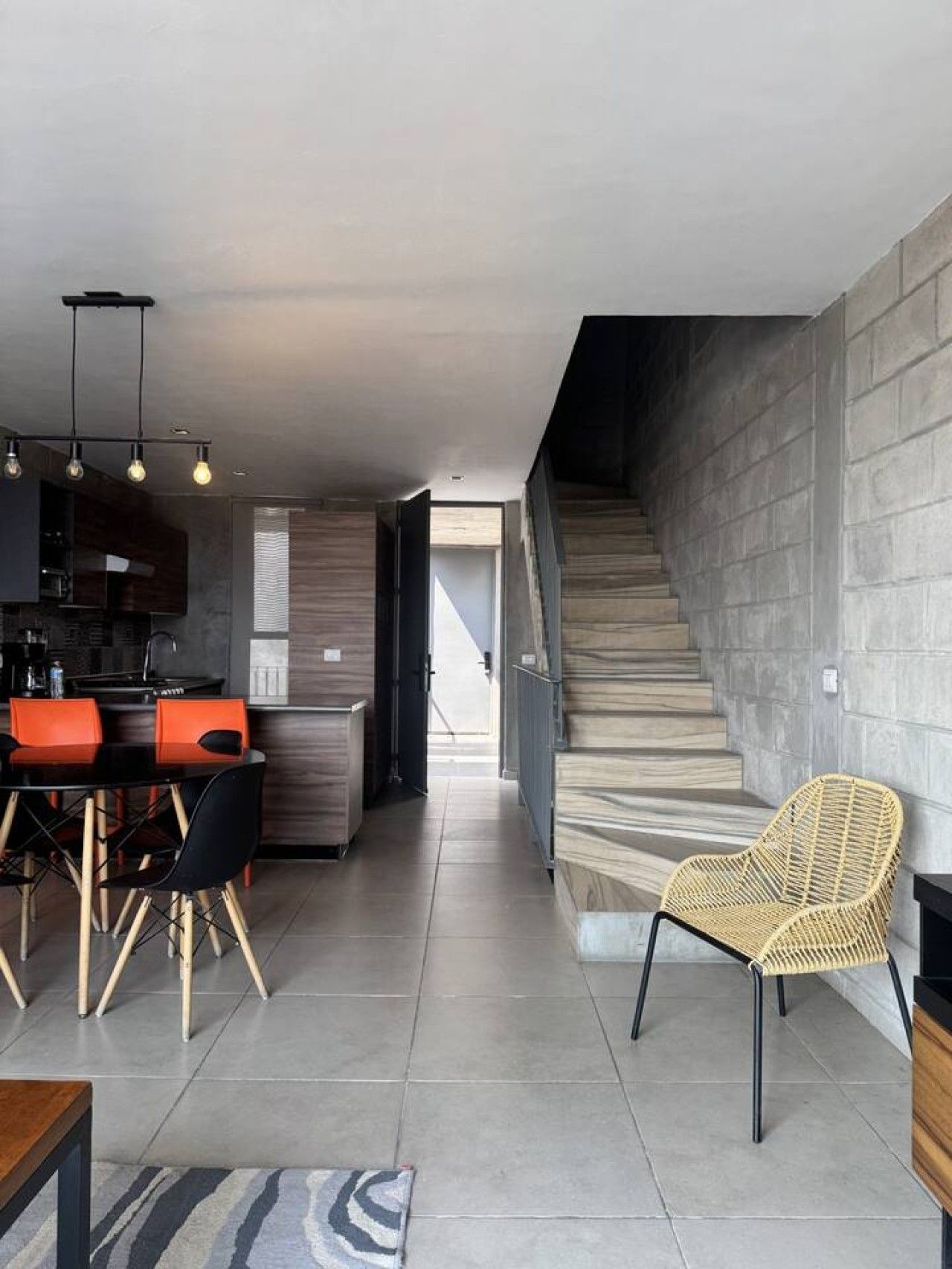 A modern interior with a kitchen, dining area, and staircase.