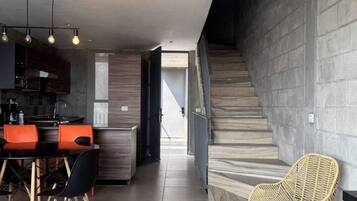 A modern interior with a kitchen, dining area, and staircase.