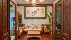 A traditional room with a wooden sofa set, a coffee table, and a large framed artwork on the wall.