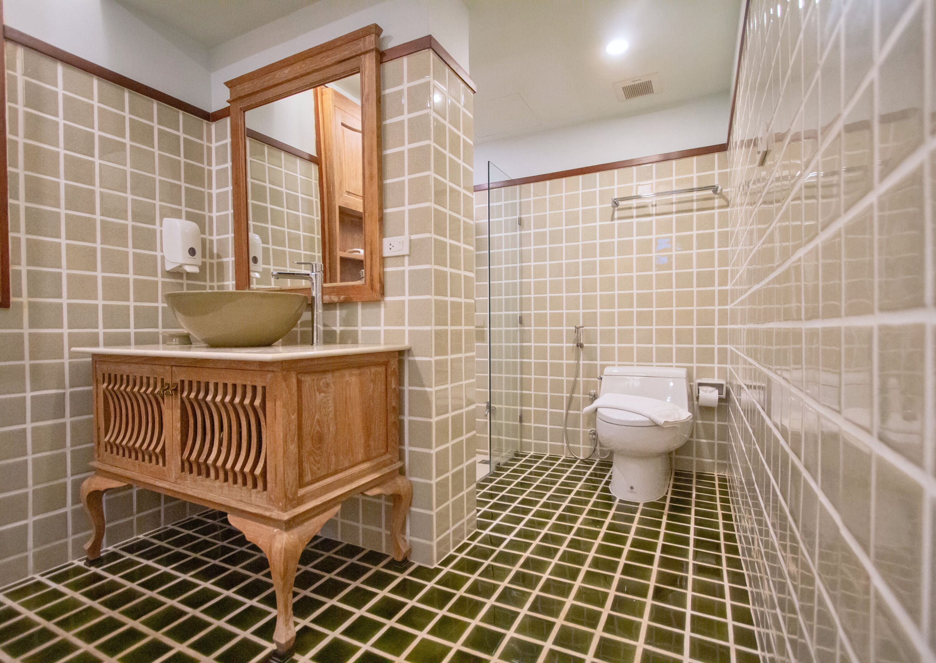 Een badkamer met een houten wastafelmeubel, een wastafel op standaard, een toilet en een douchecabine van glas.