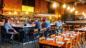 Ein Restaurant mit Barbereich, Holztischen und -stühlen.