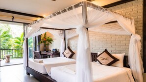 A double bed with a canopy, two pillows with the word "Casa" on them, a ceiling fan, and a brick wall. - Puluong Casa Resort (Pu Luong)