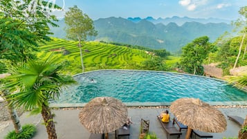 A pool with a view of terraced fields and mountains.