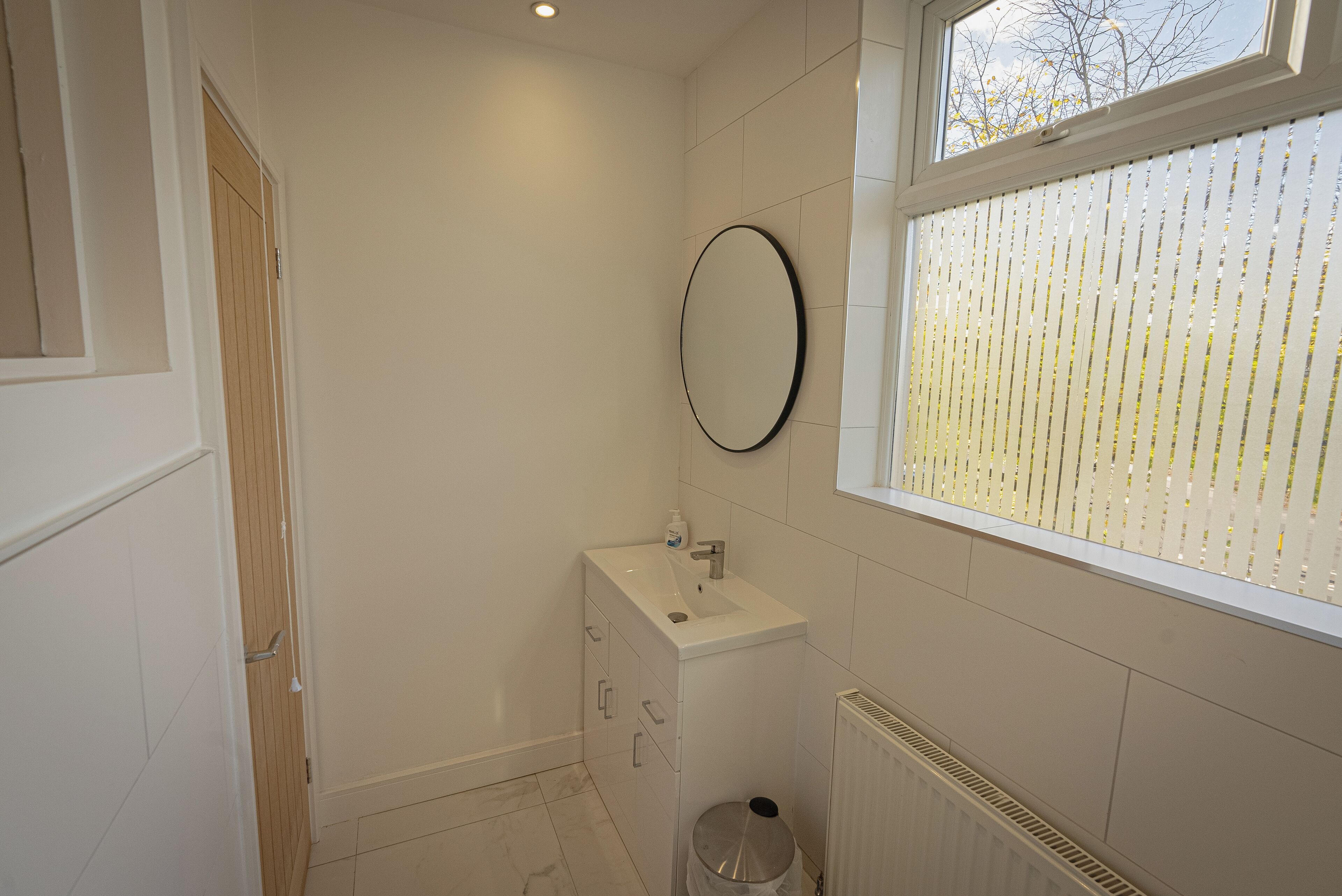 A bathroom with a white sink, mirror, and radiator.