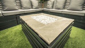 A modern outdoor seating area with a stone table and cushions. - OYO Bellevue Apartments Middlesborough (Middlesbrough)