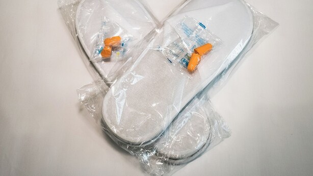 A pair of gray slippers and two pairs of white slippers in plastic packaging. - OYO Bellevue Apartments Middlesborough (Middlesbrough)