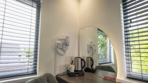 A hotel room with a wooden desk, two wall-mounted coffee makers, a cup, and a chair. - OYO Bellevue Apartments Middlesborough (Middlesbrough)