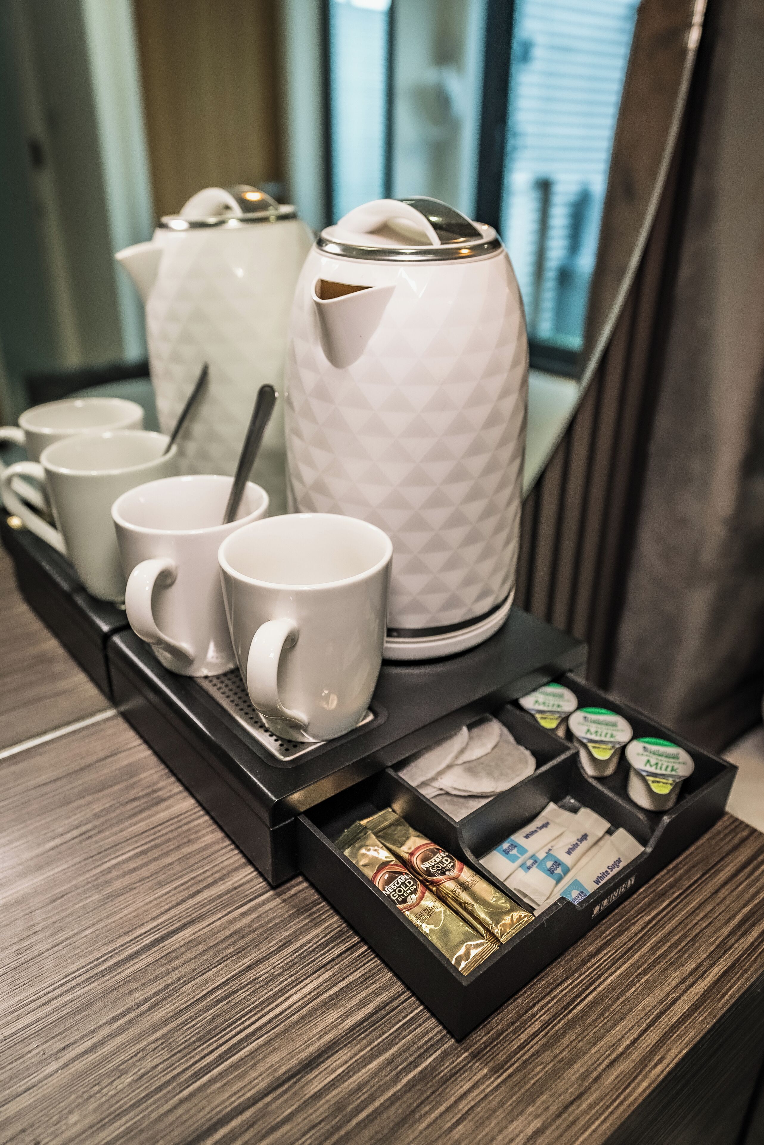 A coffee station with a coffee maker, mugs, and coffee pods.