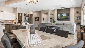 Una cocina moderna con comedor, una isla integrada y un televisor de pantalla plana grande montado en la pared.