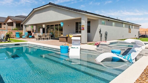 Una casa moderna con piscina, mobiliario exterior y zona de barbacoa.