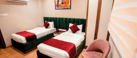 A hotel room with two beds, a green upholstered headboard, a pink chair, and a painting on the wall.
