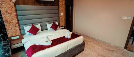 Una cama bien tendida con ropa de cama blanca y detalles en rojo, un cabecero de madera y un suelo de mármol.