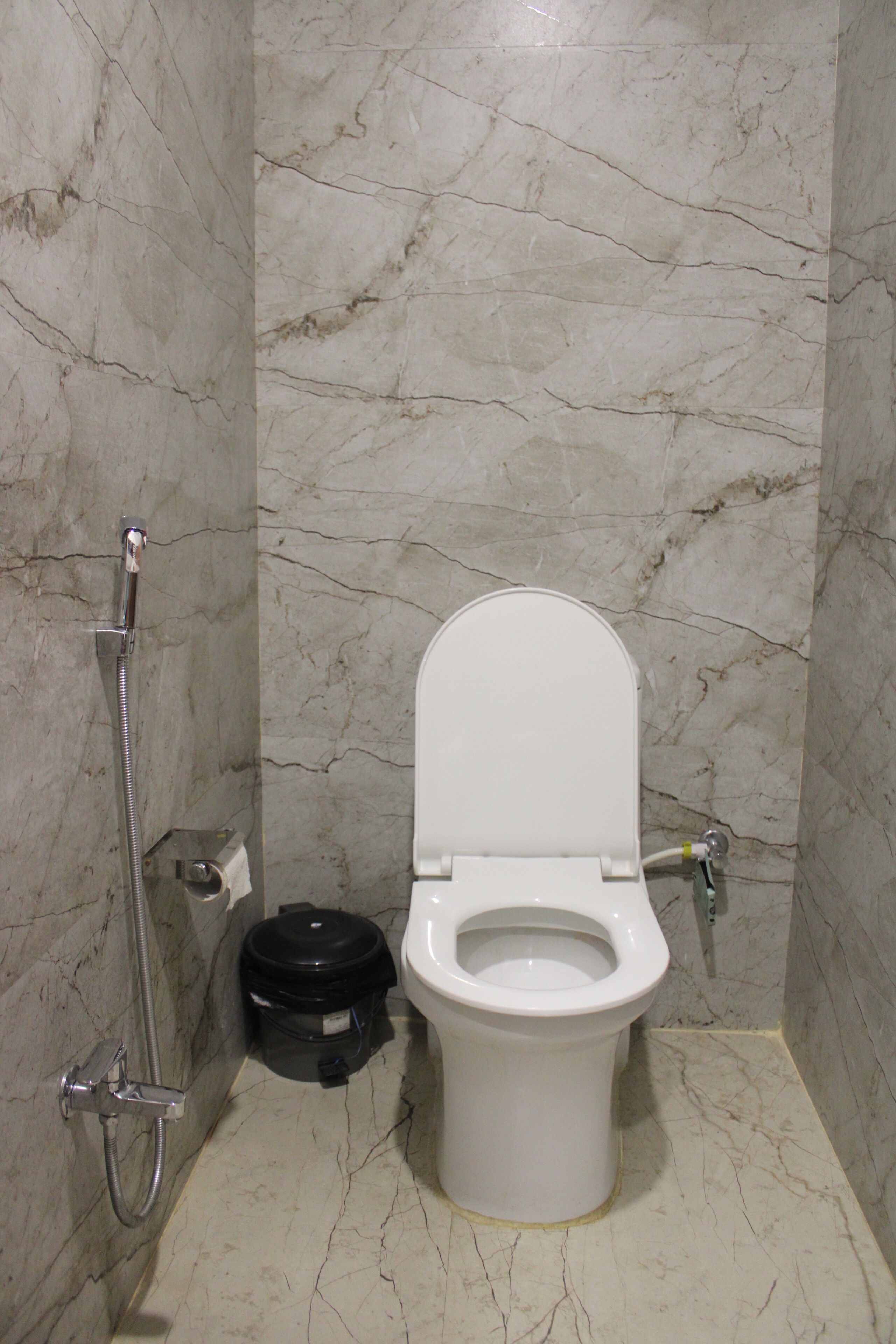 A bathroom with a toilet, a shower, and a vacuum cleaner.