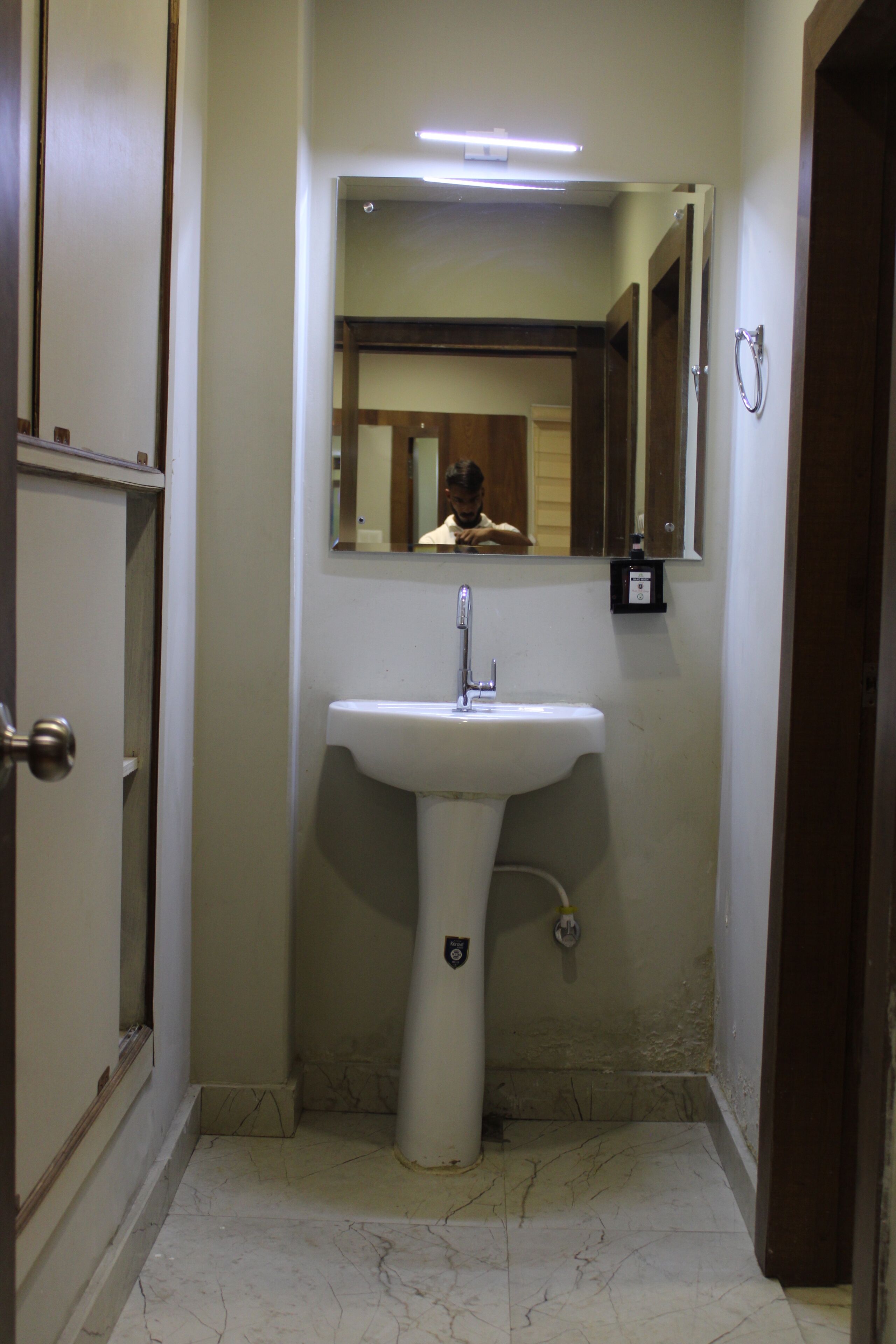 Une salle de bain avec un lavabo blanc, un miroir et des toilettes.