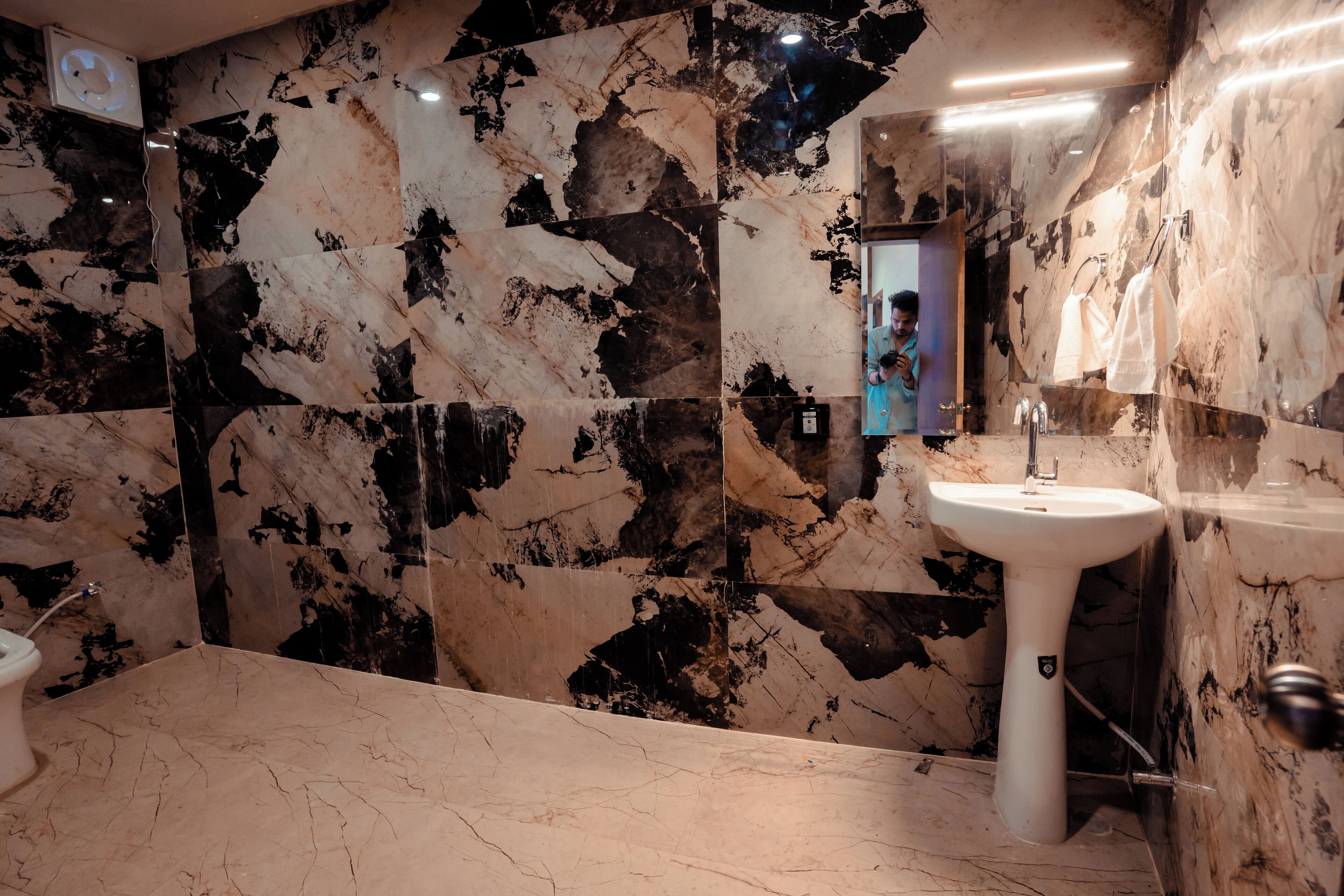 A bathroom with a marble sink, a mirror, and a toilet.