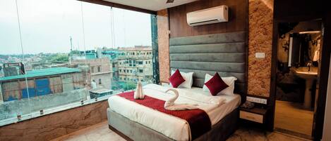 Habitación de hotel moderna con una cama grande, ventilador de techo, equipo de aire acondicionado y vista a la ciudad.