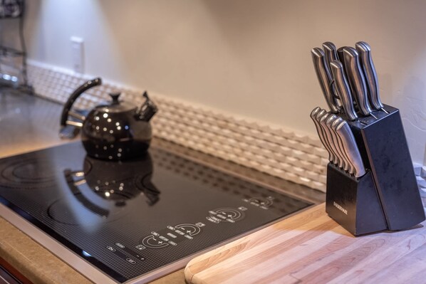 Una encimera de cocina con una tetera, un bloque de cuchillos y un teclado.