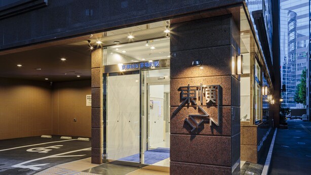 Entrada de hotel con diseño moderno, destacándose un cartel llamativo y acceso despejado.